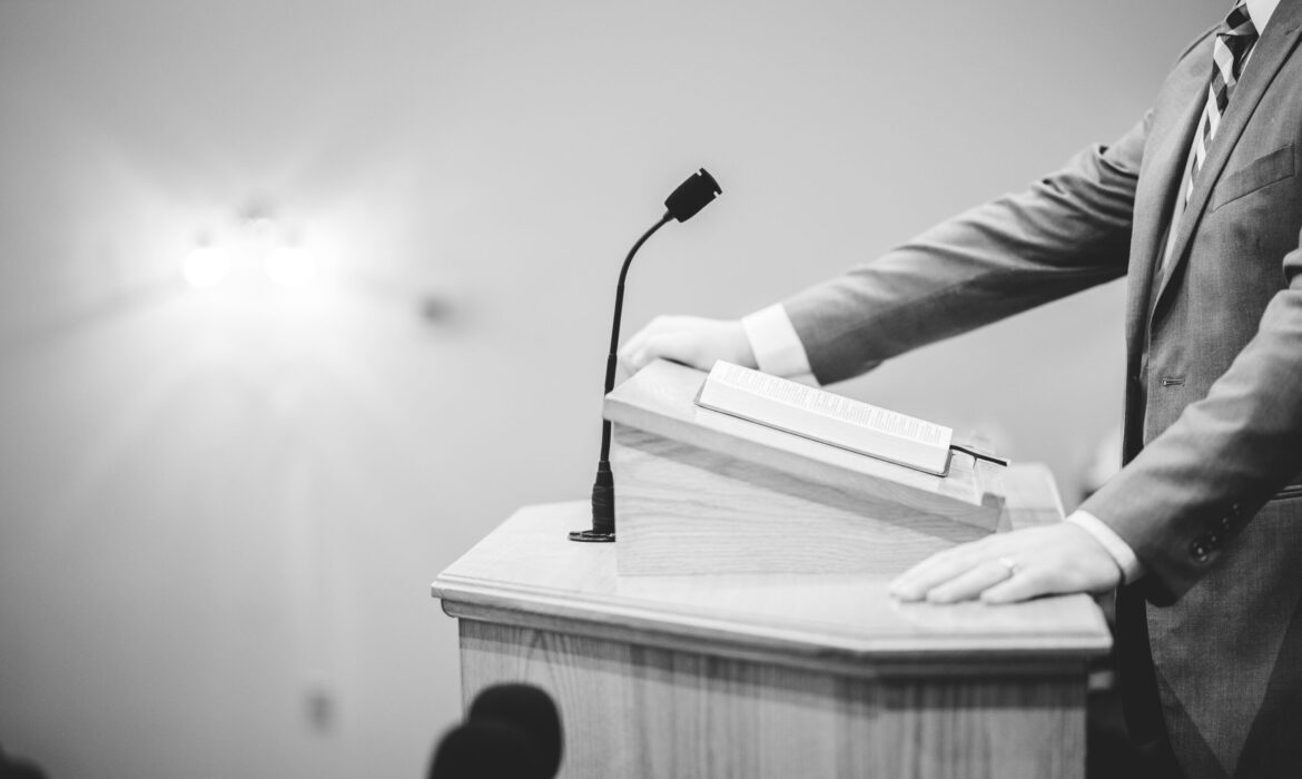 grayscale-shot-male-speaking-podium